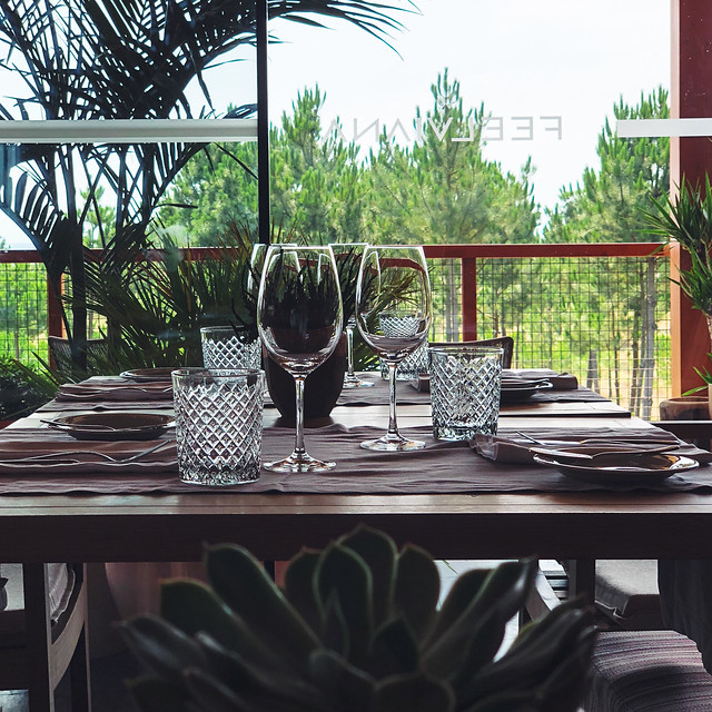 Detalhe de uma das mesas do FeelViana Restaurante, com amplas janelas de vidro e vista privilegiada para o pinhal do Cabedelo. 